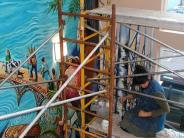 woman painting mural inside the library