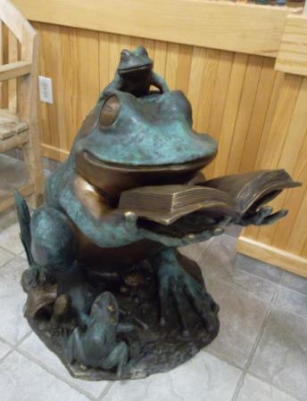 Metal frog sculpture reading a book